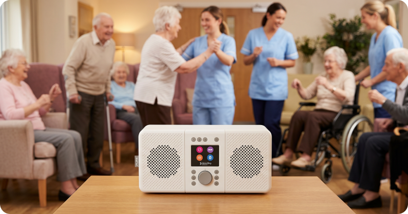 A group of residents and care staff dancing and laughing around a danceSing radio unit on a wooden table